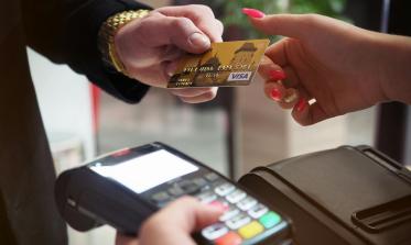 Person hands a credit card to a person holding a handheld scanner